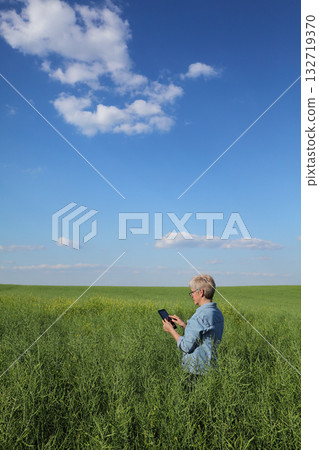 Female farmer inspecting rapeseed crop in field Female farmer inspecting rapeseed crop in field 132719370