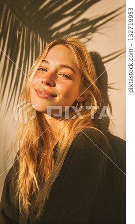 Woman With Long Hair Poses Against a Wall With Playful Shadow Patterns at Sunset 132719953