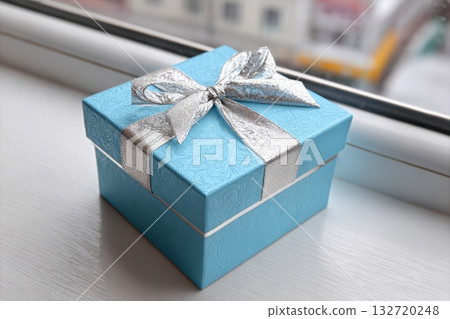Beautiful Blue Gift Box With Silver Ribbon Placed on Window Sill 132720248