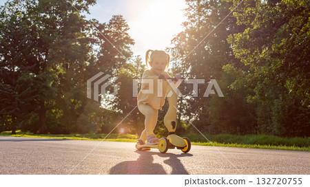 Girl on scooter. Riding child outdoor fun. Sunshine road freedom lifestyle. 132720755