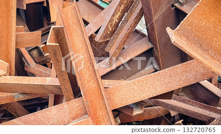 Close-up of a chaotic pile of heavily rusted metal I-beams, creating an industrial abstract background texture 132720765