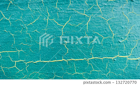 Close-up of vibrant turquoise paint with yellow cracks, creating a distressed abstract texture background 132720770