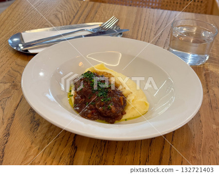 Beef stew with mashed potatoes served in white bowl on wooden table. Boeuf bourguignon. Comfort food lunch Beef stew with mashed potatoes served in white bowl on wooden table. Boeuf bourguignon. Comfort food lunch 132721403