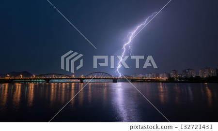 Lightning Striking Over City Bridge At Night. Dramatic Urban Landscape With Reflections On Water 132721431