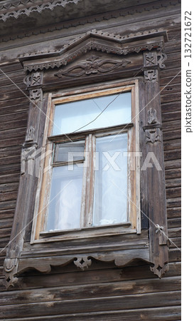 Old wooden windows with shutters on a wooden house with rustic carved designs, with intricate carvings on top Old wooden windows with shutters on a wooden house with rustic carved designs, with intricate carvings on top 132721672