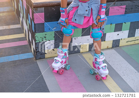 A girl rests on the ramp of a skate park while riding quad rollers A girl rests on the ramp of a skate park while riding quad rollers 132721781