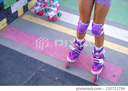 Close-up of a child's legs with knee pads on for protection when roller skating. Close-up of a child's legs with knee pads on for protection when roller skating. 132721784