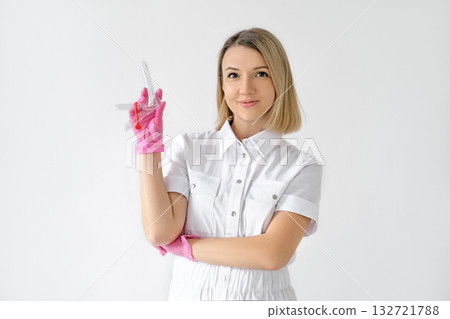 A female doctor holds a speculum in her hands on a white studio background. A medical instrument for examination in gynecology. A female doctor holds a speculum in her hands on a white studio background. A medical instrument for examination in gynecology. 132721788