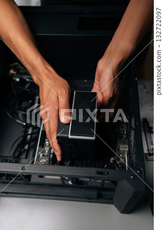 Vertical cropped shot of technician installing CPU water cooler into desktop computer case, showcasing process of computer maintenance and upgrade. Concept of desktop PC maintenance and service. Vertical cropped shot of technician installing CPU water cooler into desktop computer case, showcasing process of computer maintenance and upgrade. Concept of desktop PC maintenance and service. 132722097