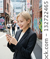 一名金髮女子在城市裡使用智慧型手機。 132722465