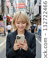 一名金髮女子在城市裡使用智慧型手機。 132722466
