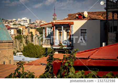 Old Wooden Balcony In Tbilisi Georgia: Weathered Architecture With Peeling Paint, Rustic Windows, And Hanging Laundry In Evening Light Old Wooden Balcony In Tbilisi Georgia: Weathered Architecture With Peeling Paint, Rustic Windows, And Hanging Laundry In Evening Light 132722598