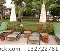 Relaxing Poolside Lounge Area With Umbrellas, Palm Trees, And Floral Garden At Resort 132722781