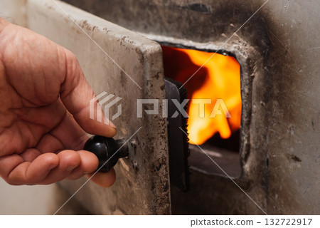 Hand of a man closing the door of solid fuel boiler. House heating, warmth at home in cold winter period 132722917