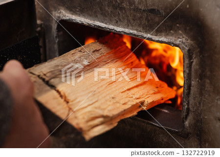 Heating the house in winter by burning firewood in solid fuel boiler. Cold season of the year, getting warm at home, no gas and electricity Heating the house in winter by burning firewood in solid fuel boiler. Cold season of the year, getting warm at home, no gas and electricity 132722919