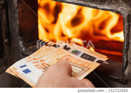 Man throwing euro money in the boiler with bright flames in it. Concept of high prices for heating the house, shortage of fuel and need to save money 132722920