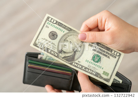 Hand of a woman with ten dollar banknote, close up, wallet on the background. Money currency of the USA, world finances, business and purchases concept Hand of a woman with ten dollar banknote, close up, wallet on the background. Money currency of the USA, world finances, business and purchases concept 132722942