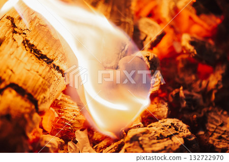 Hot coals and burning paper piece in the form of human heart, close up. Glowing and flaming coal, bright red fire and ash Hot coals and burning paper piece in the form of human heart, close up. Glowing and flaming coal, bright red fire and ash 132722970