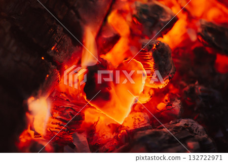 Dark red coals and burnt piece of paper in the form of heart, close up. Concept of broken heart, end of relationships and devastation Dark red coals and burnt piece of paper in the form of heart, close up. Concept of broken heart, end of relationships and devastation 132722971