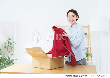 A woman putting clothes into a cardboard box 132723016