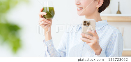 A woman drinking green juice A woman drinking green juice 132723032