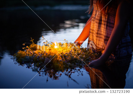 Wreath made with wild flowers with a candle in the middle. Girl following old slavic traditions on day of Ivana Kupala 132723190