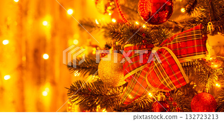 Wide photo of decorations on Christmas tree lit by warm light from garlands. Christmas mood, festive atmosphere Wide photo of decorations on Christmas tree lit by warm light from garlands. Christmas mood, festive atmosphere 132723213