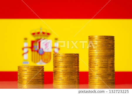 Upgoing graph made of coins stacked in front of Spain flag. Concept of financial development of Spain 132723225