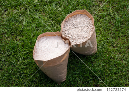 Two bags of fertilizer on grass. NPK and granulated nitrate fertilizers in paper bags Two bags of fertilizer on grass. NPK and granulated nitrate fertilizers in paper bags 132723274