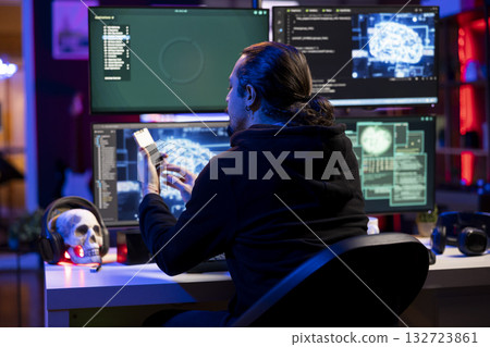 Hacker at desk coding on PC, using AI to evade security with stealth malware uploaded on SSD. Evil man using storage drive to hide malicious code from firewall detection systems 132723861