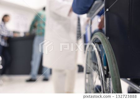 Patient with disability waits in hospital for medical consultation and recovery plan. Person in wheelchair seated in clinical lobby, ready to meet healthcare specialists for rehabilitation discussion. 132723888