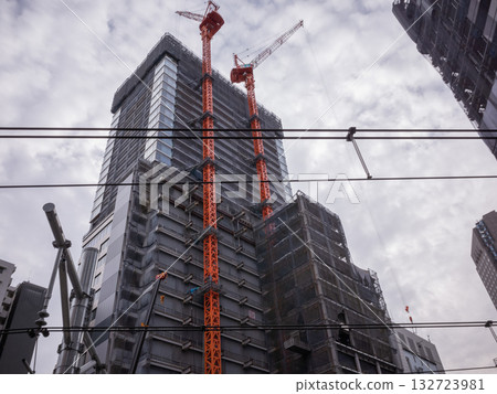 【日本】東京一棟在建建築,旁邊掛著一台橘色的起重機 【日本】東京一棟在建建築,旁邊掛著一台橘色的起重機 132723981