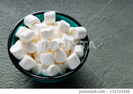 White Marshmallow Candies in Bowl on Green Background Copy Space 132724106