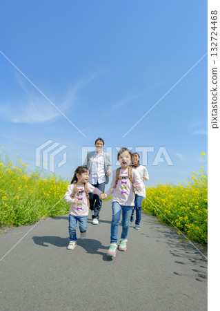 Four people walking on the promenade of rape blossoms 132724468