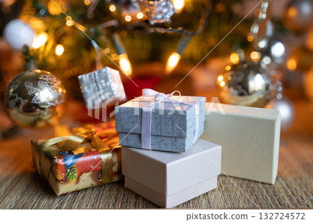 Elegant wrapped Christmas gift boxes and decorations on rustic table.lluminated Christmas tree in the blurred background Elegant wrapped Christmas gift boxes and decorations on rustic table.lluminated Christmas tree in the blurred background 132724572