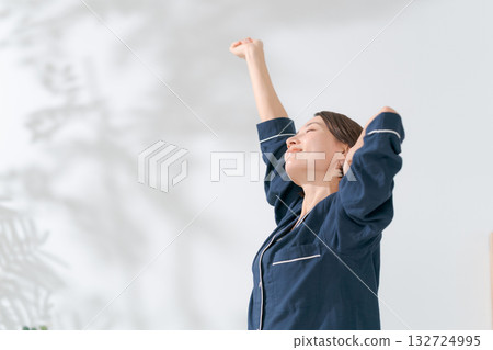 A woman in pajamas stretching 132724995