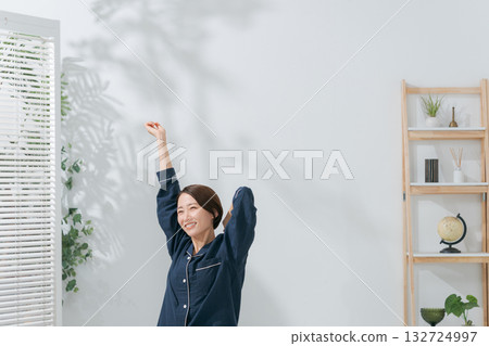 A woman in pajamas stretching 132724997