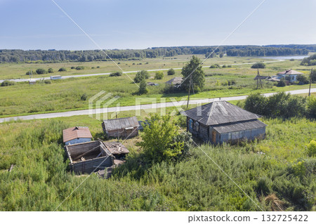 Aerial view of fields, forests and an old wooden dilapidated house near the road 132725422