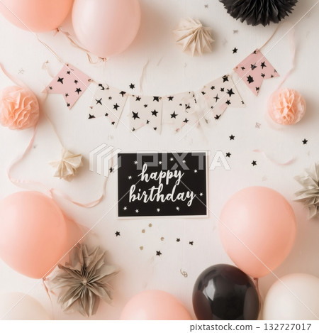 Pink and black balloons, paper decorations, and confetti create a festive atmosphere around a happy birthday card on a white wooden table, celebrating a special occasion 132727017