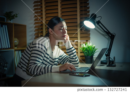 sleepy woman working with laptop at a night 132727241