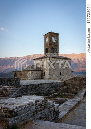 Sunset over clock tower and fortress at Gjirokaster, a beautiful town in Albania where the Ottoman legacy is clearly visible. High above the town the huge castle offers panoramic views. Sunset over clock tower and fortress at Gjirokaster, a beautiful town in Albania where the Ottoman legacy is clearly visible. High above the town the huge castle offers panoramic views. 132728024