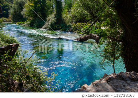 Beautiful turquoise spring Blue Eye or Syri i Kalter near Muzine town in Albania. The spring is very powerful, cold and deep and is a source of a river Bistrice. Tourist attraction of Albania. Beautiful turquoise spring Blue Eye or Syri i Kalter near Muzine town in Albania. The spring is very powerful, cold and deep and is a source of a river Bistrice. Tourist attraction of Albania. 132728163