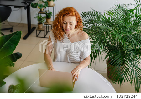 Young woman focused on her laptop while working remotely from the comfort of her home workspace. 132728244