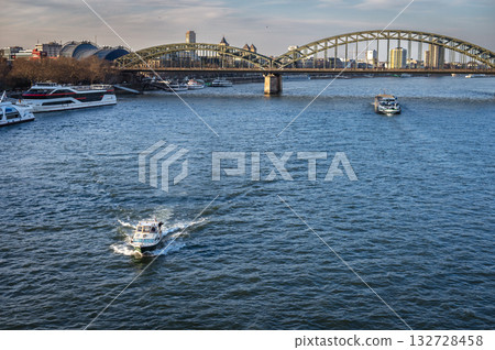 Wonderful view of Cologne over the Rhein rive and Hohenzollern Bridge in the background. Two vehicles on the river. Wonderful view of Cologne over the Rhein rive and Hohenzollern Bridge in the background. Two vehicles on the river. 132728458