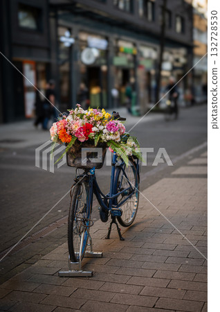 Bycicle parked in the street in Cologne with flowers in busket. Cologne street in the background. 132728530