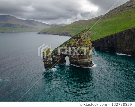 Close-up shot of famous Drangarnir cliff with Tindholmur islands in the background taken during early morning hike in spring at Faroese coastline Faroe Island, Denmark, Europe. High quality photo 132728539