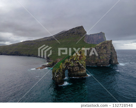 Close-up shot of famous Drangarnir cliff with Tindholmur islands in the background taken during early morning hike in spring at Faroese coastline Faroe Island, Denmark, Europe. High quality photo 132728548