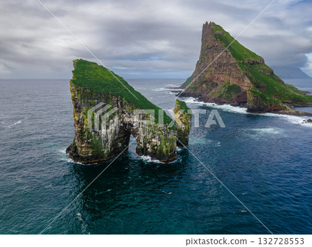 Close-up shot of famous Drangarnir cliff with Tindholmur islands in the background taken during early morning hike in spring at Faroese coastline Faroe Island, Denmark, Europe. High quality photo 132728553