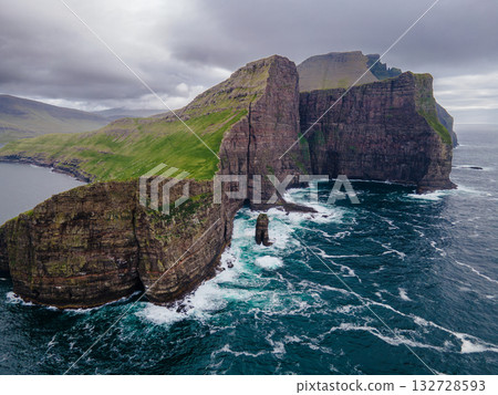 Close-up shot of famous Drangarnir cliff with Tindholmur islands in the background taken during early morning hike in spring at Faroese coastline Faroe Island, Denmark, Europe. High quality photo 132728593