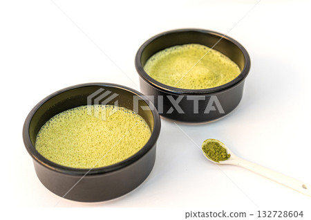 A vibrant green matcha drink alongside a bowl of fine matcha powder, presented on a clean white background for a fresh and minimalistic look. A vibrant green matcha drink alongside a bowl of fine matcha powder, presented on a clean white background for a fresh and minimalistic look. 132728604